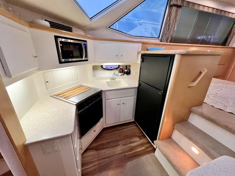Slide: The Image of 1998 Carver 405 Aft Cabin kitchen with modern appliances and wood flooring. - 10