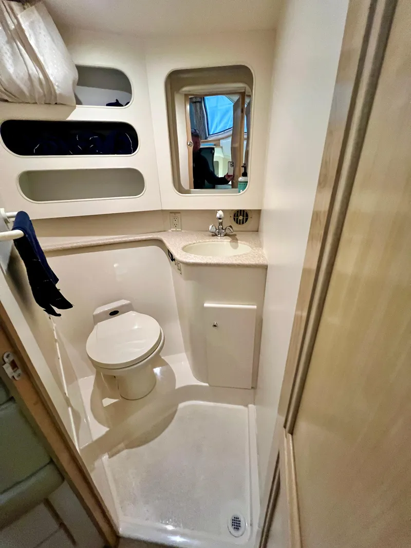 Slide: The Image of 1998 Carver 405 Aft Cabin bathroom with toilet, sink, and mirror. - 24