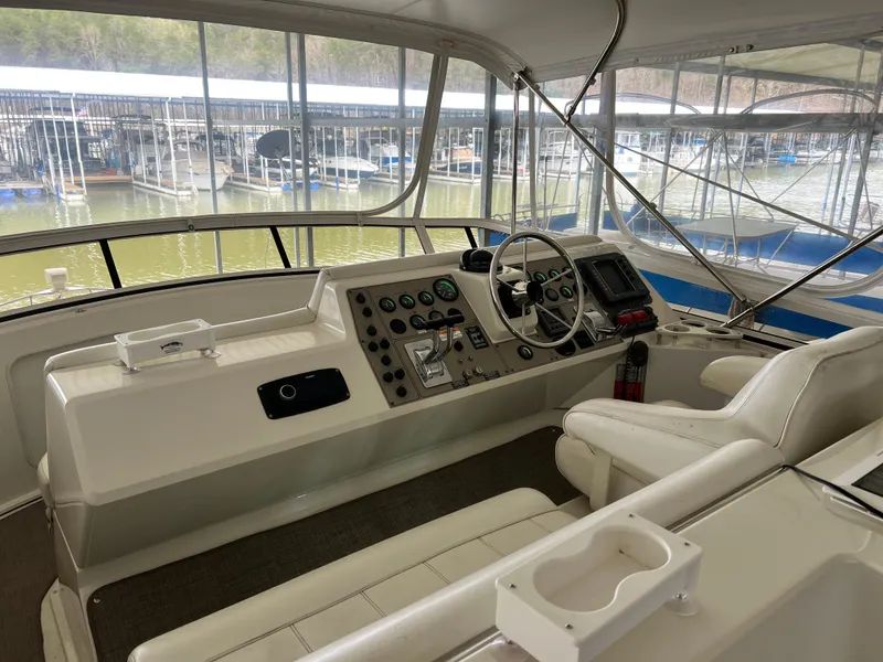 Slide: The Image of 1998 Carver 405 Aft Cabin helm with controls, steering wheel, and marina view. - 26