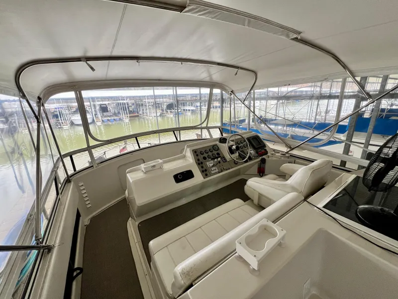Slide: The Image of 1998 Carver 405 Aft Cabin yacht interior with helm, seating, and marina view. - 27