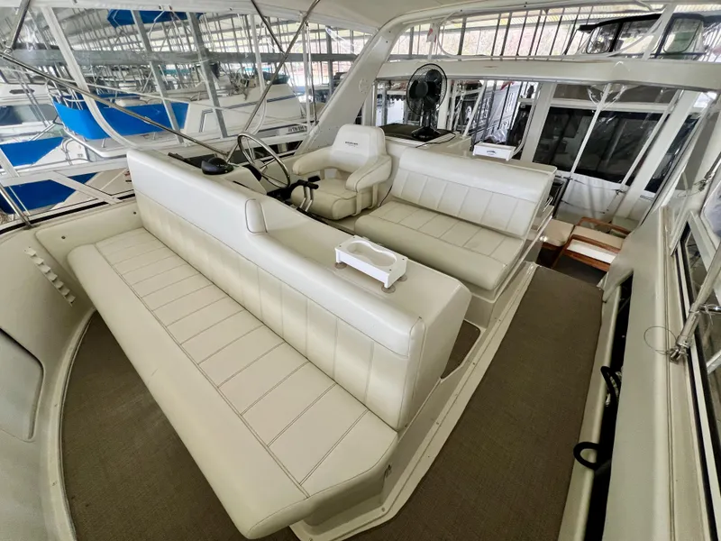 Slide: The Image of 1998 Carver 405 Aft Cabin interior with white seating and helm in a marina setting. - 29