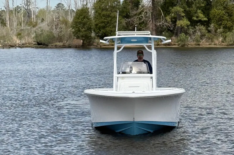Slide: The Image of 2021 Sportsman Heritage 231 Center Console boat on calm water, surrounded by trees. - 18