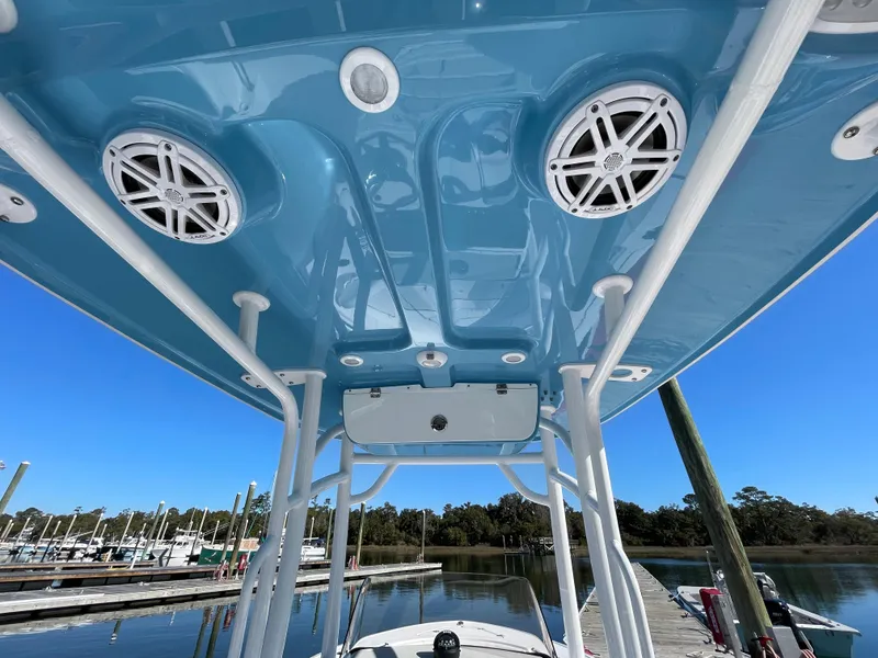 Slide: The Image of 2021 Sportsman Heritage 231 Center Console boat with blue T-top and speakers at marina. - 30