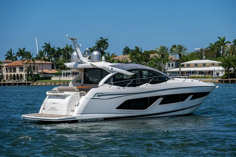 Slide: The Image of 2019 Sunseeker Predator 50 yacht cruising on a sunny day near luxury waterfront homes. - 6
