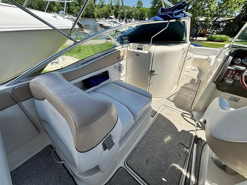 Slide: The Image of 2009 Sea Ray 290 Sundeck interior with seating and helm, docked near other boats. - 13