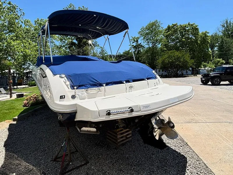 Slide: The Image of 2009 Sea Ray 290 Sundeck boat with blue cover, parked on gravel. - 2