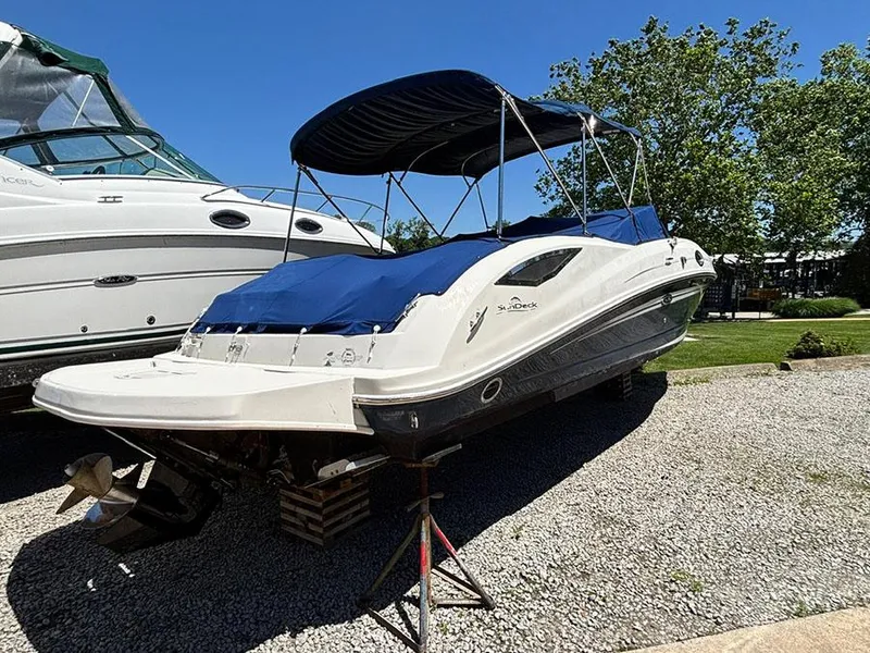 Slide: The Image of 2009 Sea Ray 290 Sundeck boat on gravel, covered with blue canopy. - 3