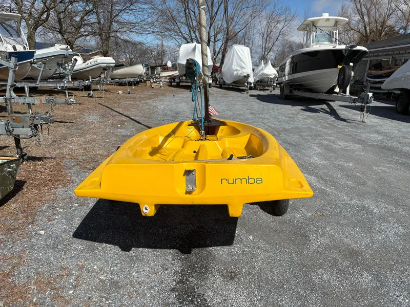 Slide: The Image of Yellow Captiva Escape 2002 sailboat named "Rumba" on a gravel lot with other boats. - 5