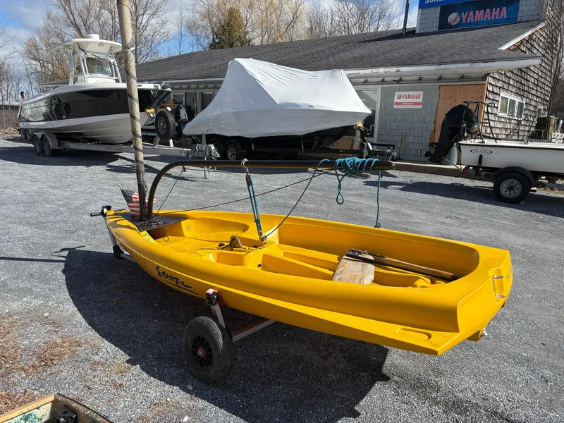 Slide: The Image of Yellow 2002 Captiva Escape sailboat on trailer, parked outdoors near other boats. - 6