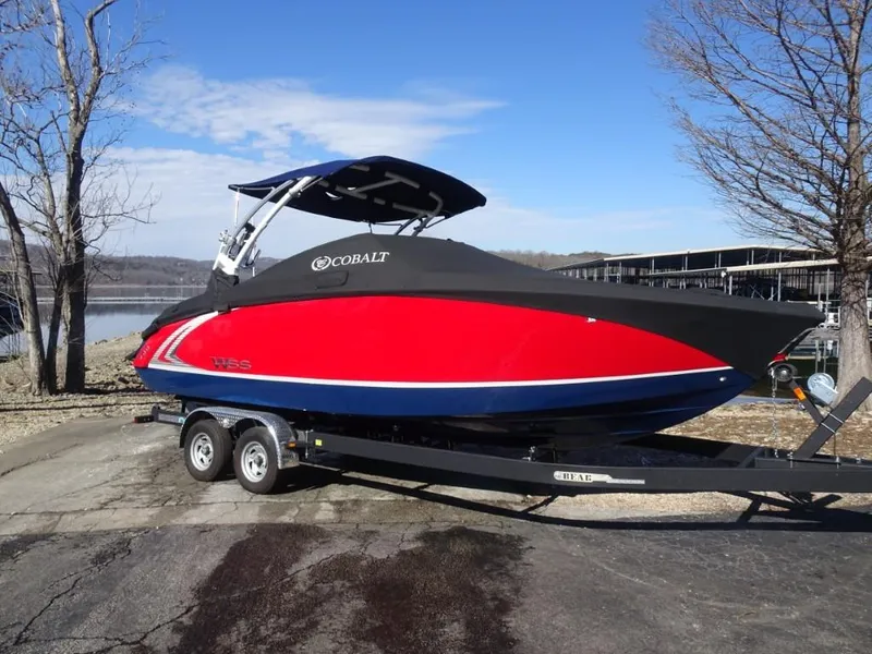 Slide: The Image of 2018 Cobalt R5 Surf boat in vibrant red on a trailer by a lakeside. - 22