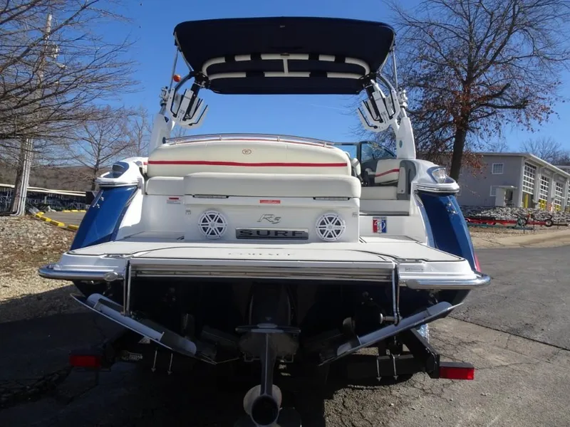 Slide: The Image of 2018 Cobalt R5 Surf boat, rear view with seating and speakers, parked outdoors. - 3