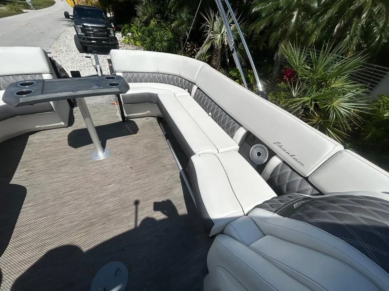 Slide: The Image of 2021 Bennington 30 boat interior with plush seating and table, surrounded by lush greenery. - 16