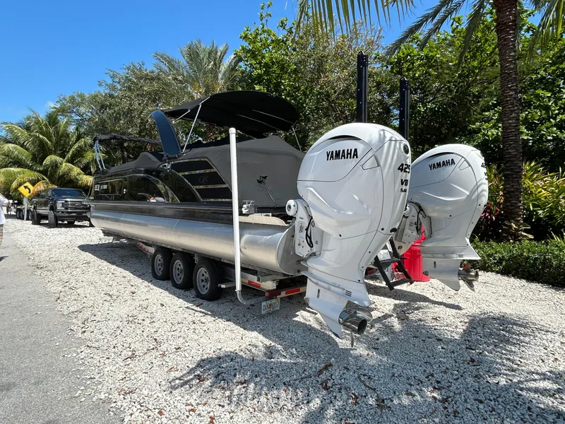 Slide: The Image of 2021 Bennington 30 boat with Yamaha engines on a trailer, parked on a gravel path. - 4