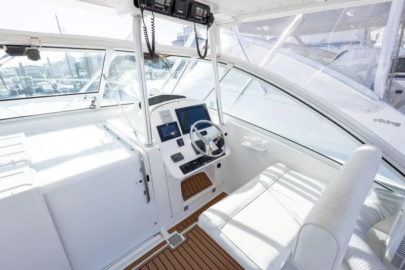 Slide: The Image of 2005 Luhrs 36 boat cockpit with steering wheel, navigation screens, and white seating. - 16