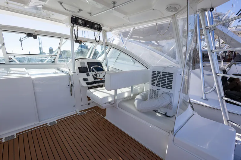 Slide: The Image of 2005 Luhrs 36 boat cockpit with steering wheel, white seating, and wood flooring. - 18