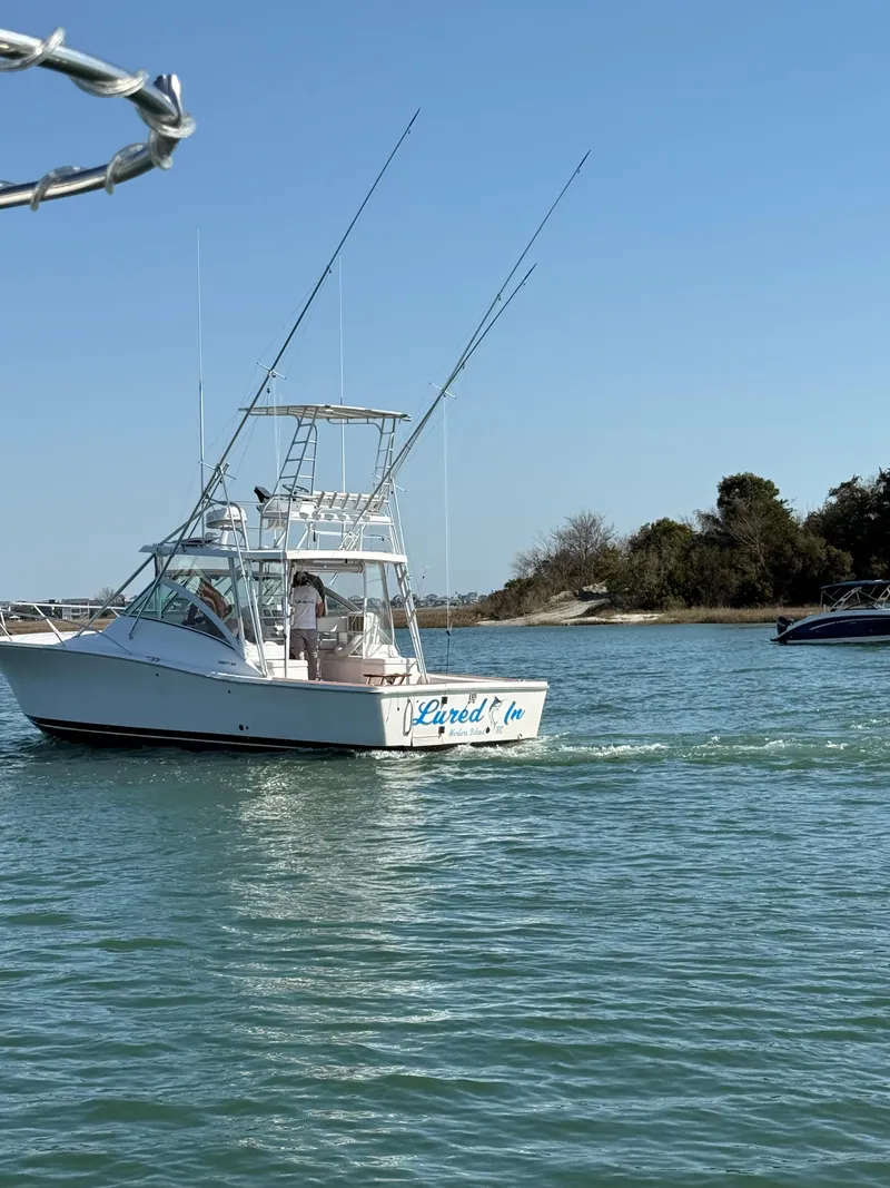 Slide: The Image of 2005 Luhrs 36 boat cruising on calm waters near a wooded shoreline. - 4