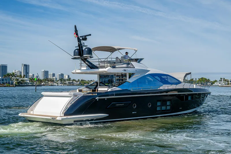 Slide: The Image of 2019 Azimut S7 yacht cruising on water with city skyline in background. - 2