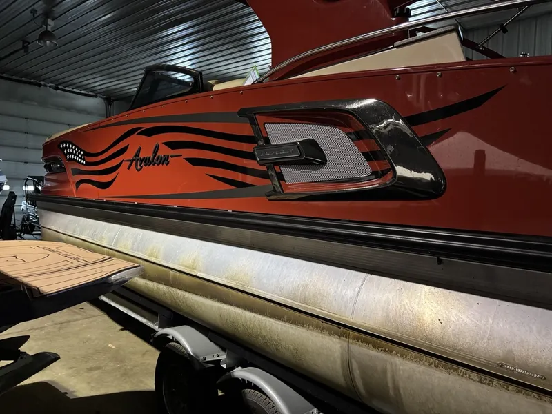 Slide: The Image of 2022 Avalon Excalibur Elite Windshield boat in a garage, showcasing sleek design and graphics. - 0
