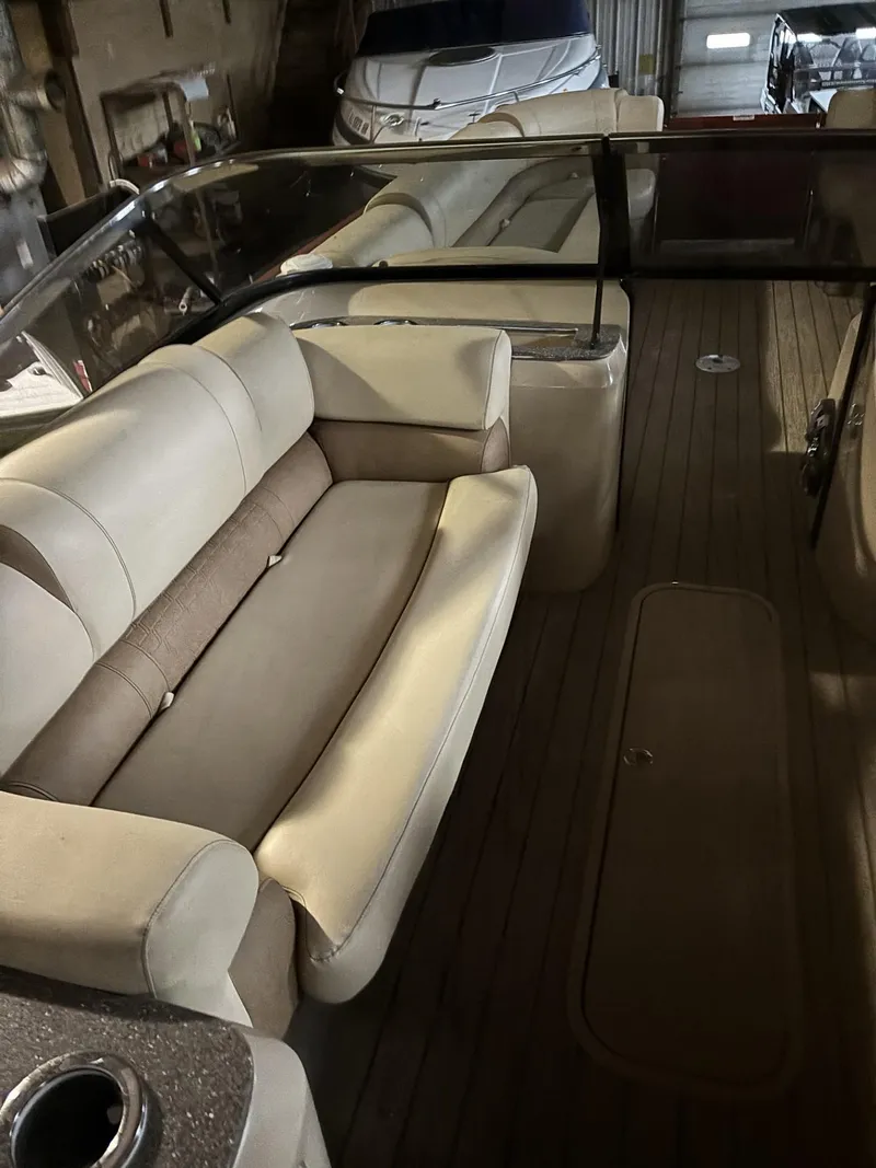 Slide: The Image of 2022 Avalon Excalibur Elite Windshield boat interior with beige seating and wooden flooring. - 15