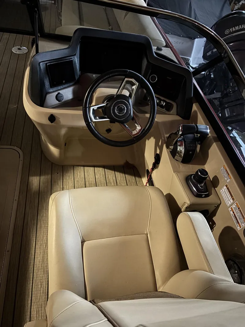 Slide: The Image of 2022 Avalon Excalibur Elite Windshield boat interior with steering wheel and beige seating. - 16