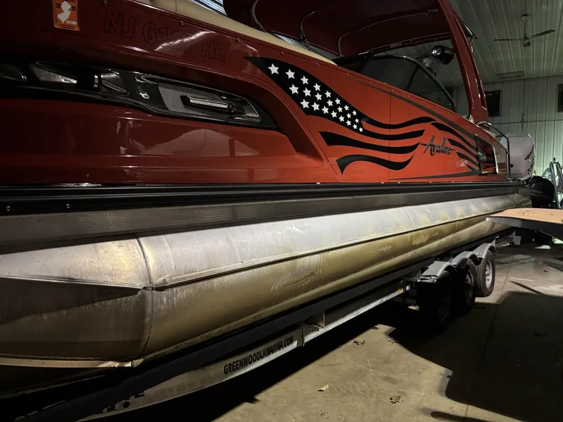 Slide: The Image of 2022 Avalon Excalibur Elite Windshield boat with American flag design in a garage setting. - 28