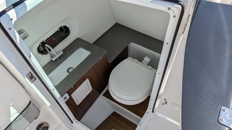 Slide: The Image of 2025 Four Winns HD8 OB boat interior with compact bathroom, featuring a sink and toilet. - 18