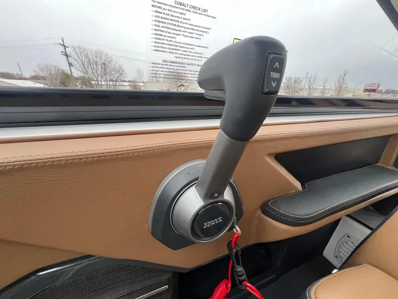 Slide: The Image of 2023 Cobalt A29 boat throttle control with trim buttons, featuring tan interior. - 18