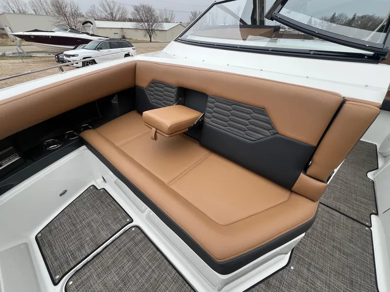 Slide: The Image of 2023 Cobalt A29 boat interior with tan and black seating, cup holders, and carpeted flooring. - 9