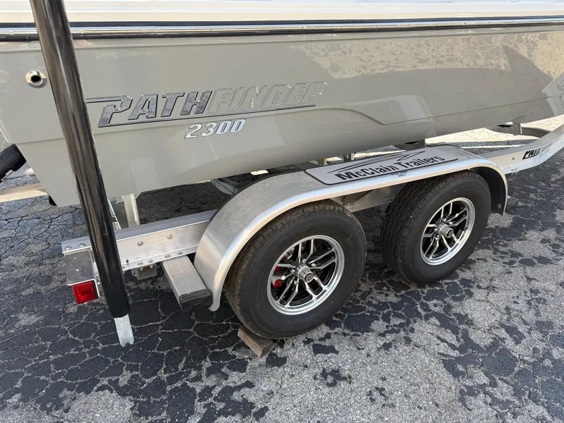 Slide: The Image of 2025 Pathfinder 2300 HPS boat on a dual-axle trailer, parked on asphalt. - 10