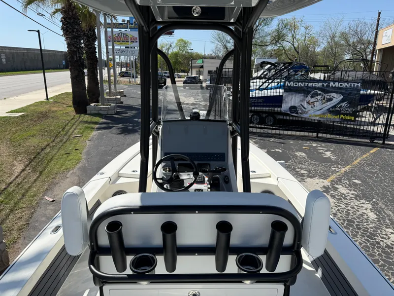 Slide: The Image of 2025 Pathfinder 2300 HPS boat interior with steering console and rod holders, parked outdoors. - 21