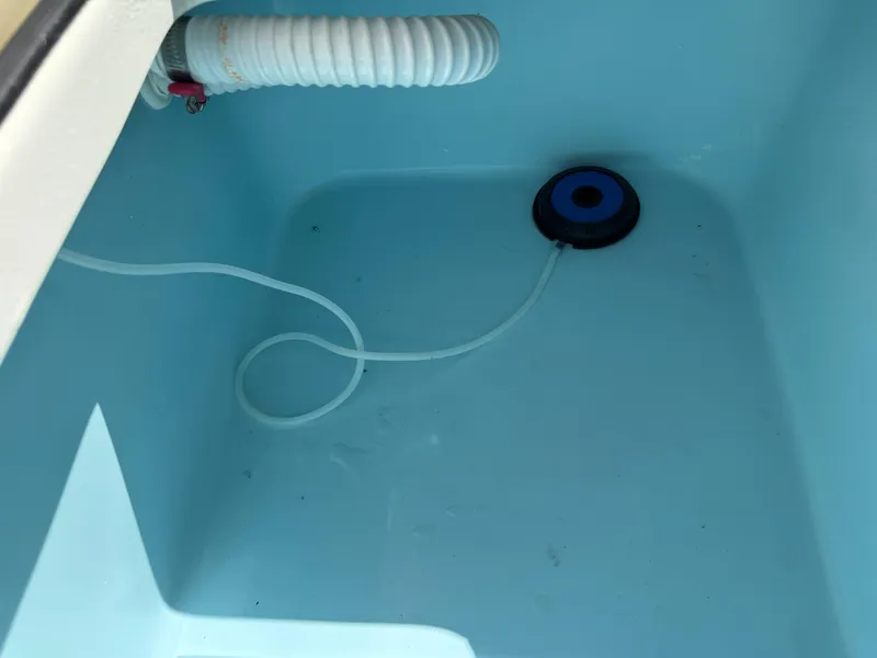 Slide: The Image of Livewell interior of 2025 Pathfinder 2300 HPS boat, featuring hose and aerator. - 25