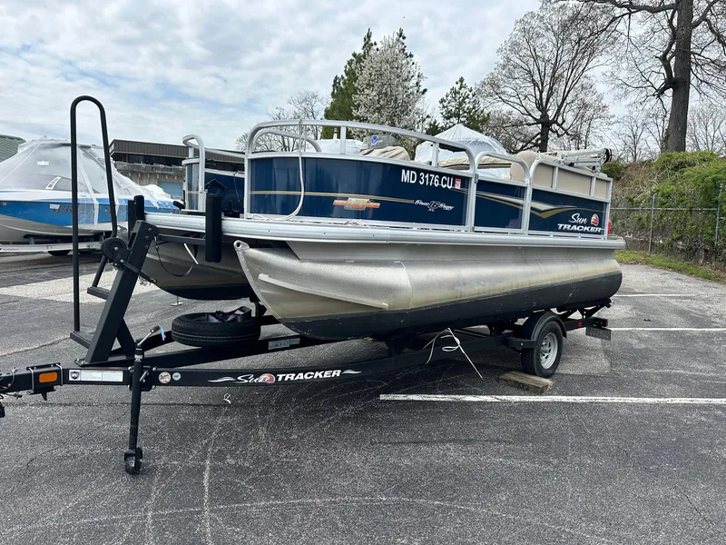 Slide: The Image of 2023 Sun Tracker Bass Buggy 16 XL Select pontoon boat on trailer in parking lot. - 2