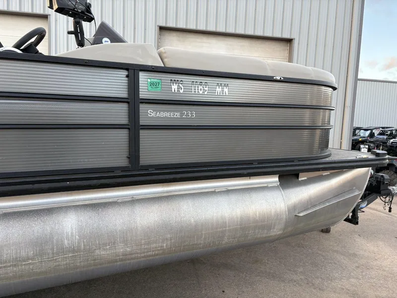 Slide: The Image of 2018 Cypress Cay Seabreeze 233 pontoon boat parked near a metal building. - 10