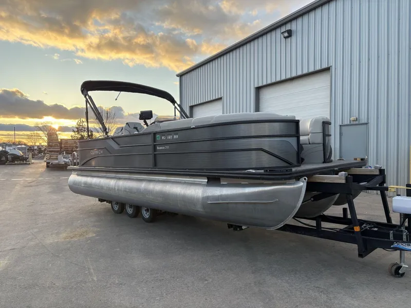 Slide: The Image of 2018 Cypress Cay Seabreeze 233 pontoon boat on trailer at sunset near warehouse. - 4