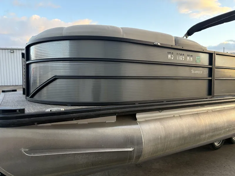 Slide: The Image of 2018 Cypress Cay Seabreeze 233 pontoon boat, side view, docked under a blue sky. - 8