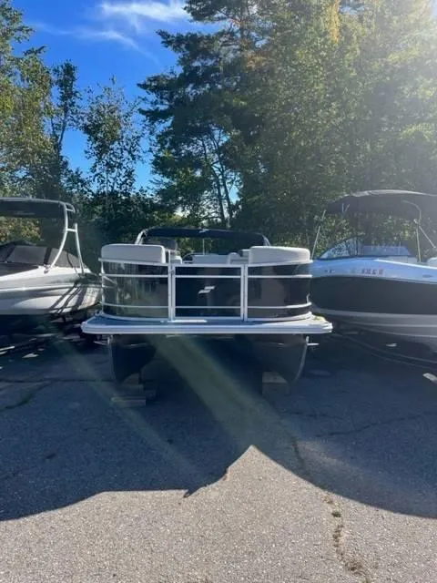 Slide: The Image of 2023 Starcraft EX 20C pontoon boat parked outdoors, surrounded by trees and other boats. - 3