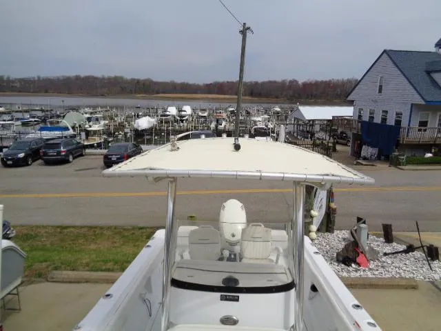 Slide: The Image of 2008 Triumph 215 CC boat docked at a marina with multiple boats and a house nearby. - 16