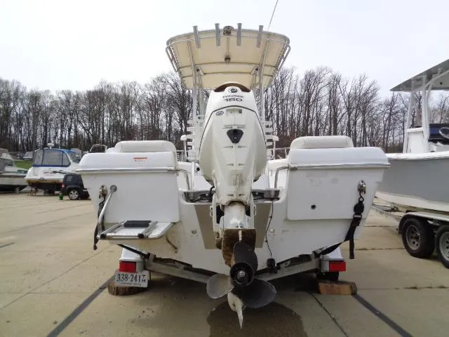 Slide: The Image of 2008 Triumph 215 CC boat with outboard motor, parked on a trailer in a marina. - 5