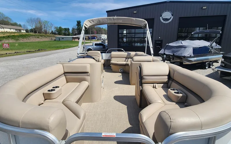 Slide: The Image of 2018 Berkshire 22CL CTS pontoon boat with beige seating, parked outdoors near a building. - 4