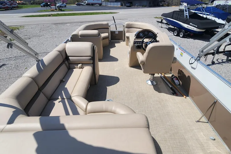 Slide: The Image of 2018 Berkshire 22CL CTS pontoon boat with beige seating and steering console, parked on gravel. - 9