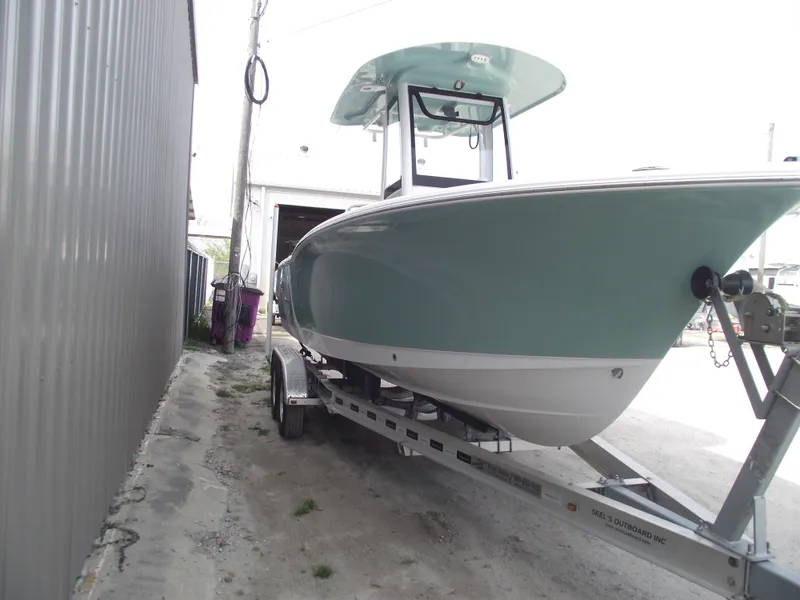 Slide: The Image of 2024 Sea Hunt Ultra 239 SE boat on trailer, parked beside a building. - 2
