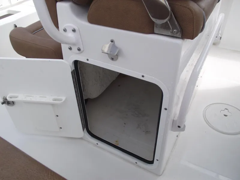 Slide: The Image of 2024 Sea Hunt Ultra 239 SE boat storage compartment with open door and brown seating. - 37