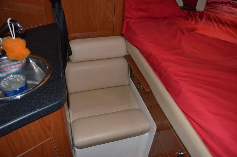 Slide: The Image of 2008 Regal 3360 Window Express interior with beige seating, red bedding, and compact kitchenette. - 12