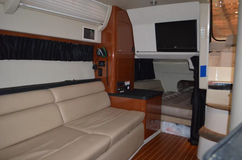 Slide: The Image of 2008 Regal 3360 Window Express interior with beige seating, wood accents, and a mounted TV. - 14