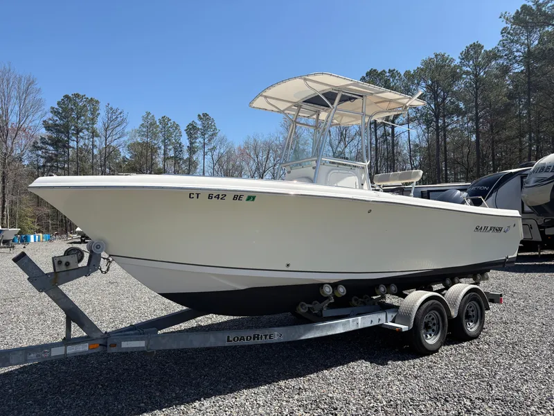 Slide: The Image of 2011 Sailfish 218 boat on trailer, parked outdoors, surrounded by trees and RVs. - 1