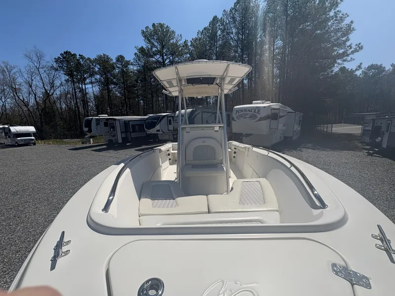 Slide: The Image of 2011 Sailfish 218 boat with T-top, parked on gravel, surrounded by trees and RVs. - 6