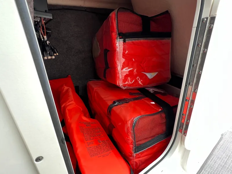 Slide: The Image of Storage compartment with red life jackets in a 2019 Chaparral 23 H2O Surf boat. - 13