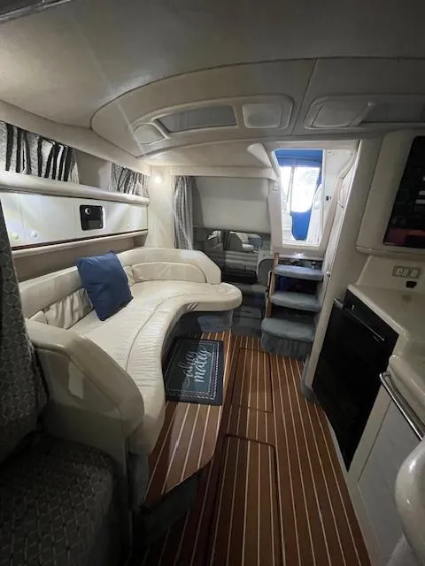 Slide: The Image of 1996 Sea Ray 330 Sundancer interior with curved seating, wood flooring, and compact kitchen area. - 24