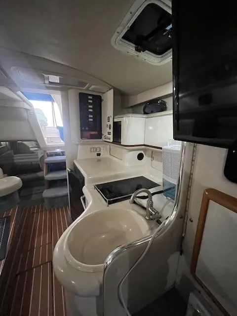 Slide: The Image of Interior of 1996 Sea Ray 330 Sundancer yacht, featuring a compact kitchen and modern amenities. - 25