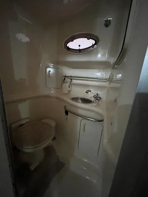 Slide: The Image of 1996 Sea Ray 330 Sundancer bathroom with sink, toilet, and porthole window. - 28